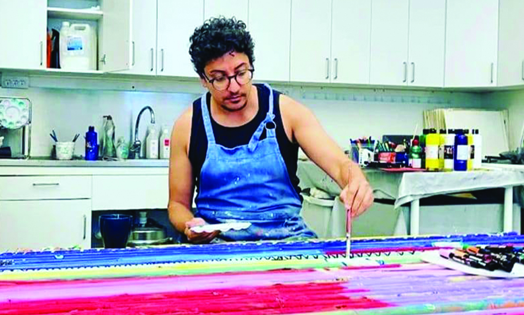 Konstnären Ward Saara sitter vid ett bord och målar